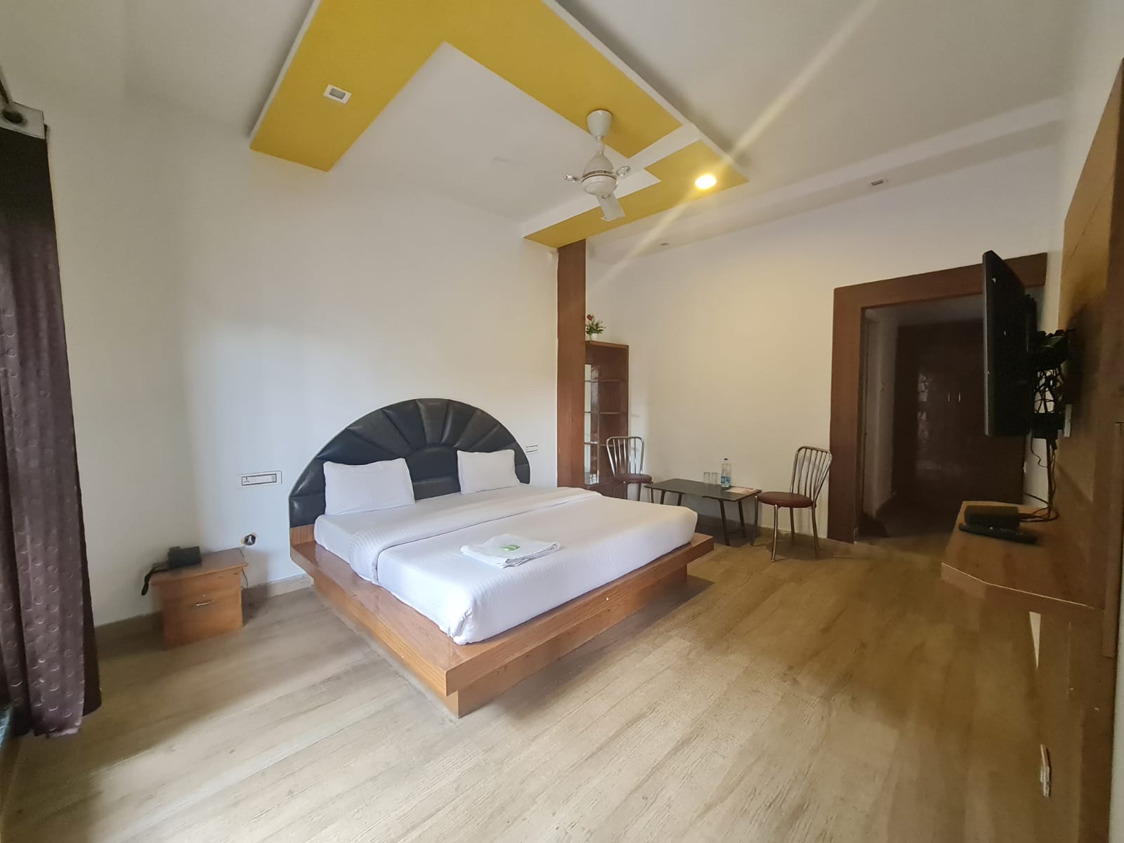 Angle highlighting the suite's stylish yellow‑accented ceiling and modern ceiling fan setup.